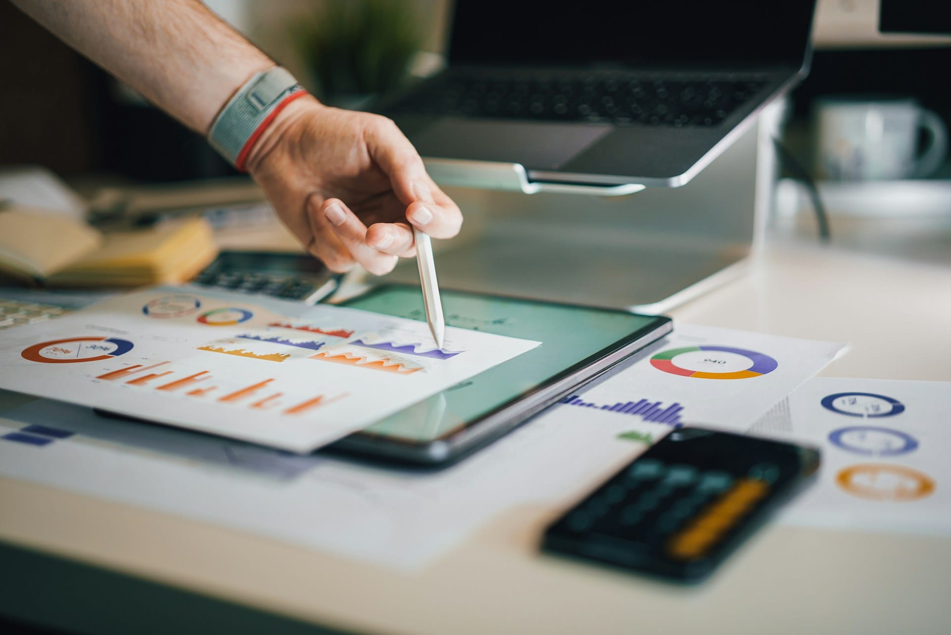 Una mano annota grafici e statistiche su un tablet appoggiato alla scrivania