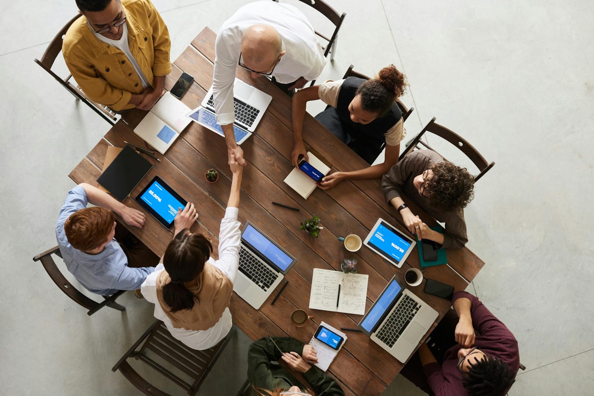 Vista dall'alto di un gruppo di docenti in formazione attorno a un tavolo con laptop e tablet