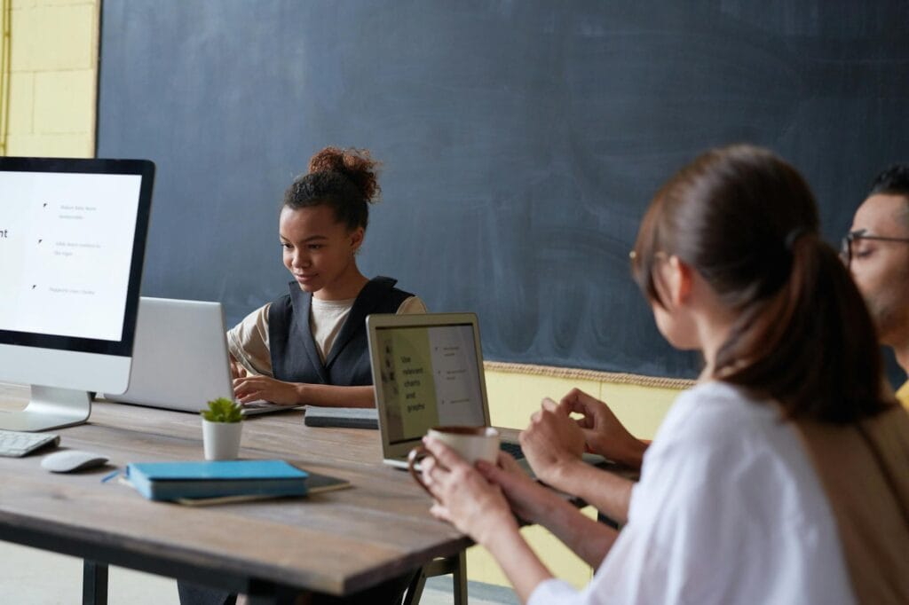 Docenti al lavoro attorno a un tavolo con laptop e tablet in un'aula