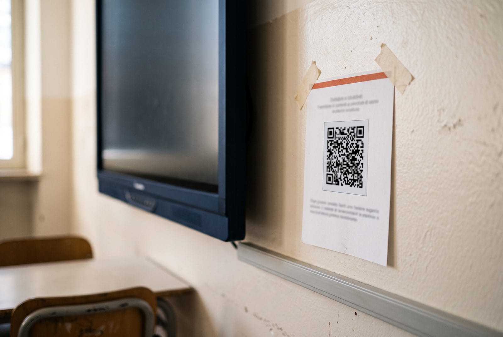 Cartellino con il codice QR appeso al muro accanto alla LIM di un'aula